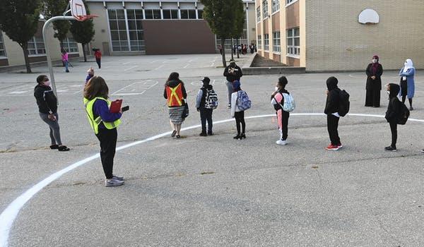People wait in a physical distancing circle at the yard at Portage Trail Community School in Toronto on Sept. 15, 2020