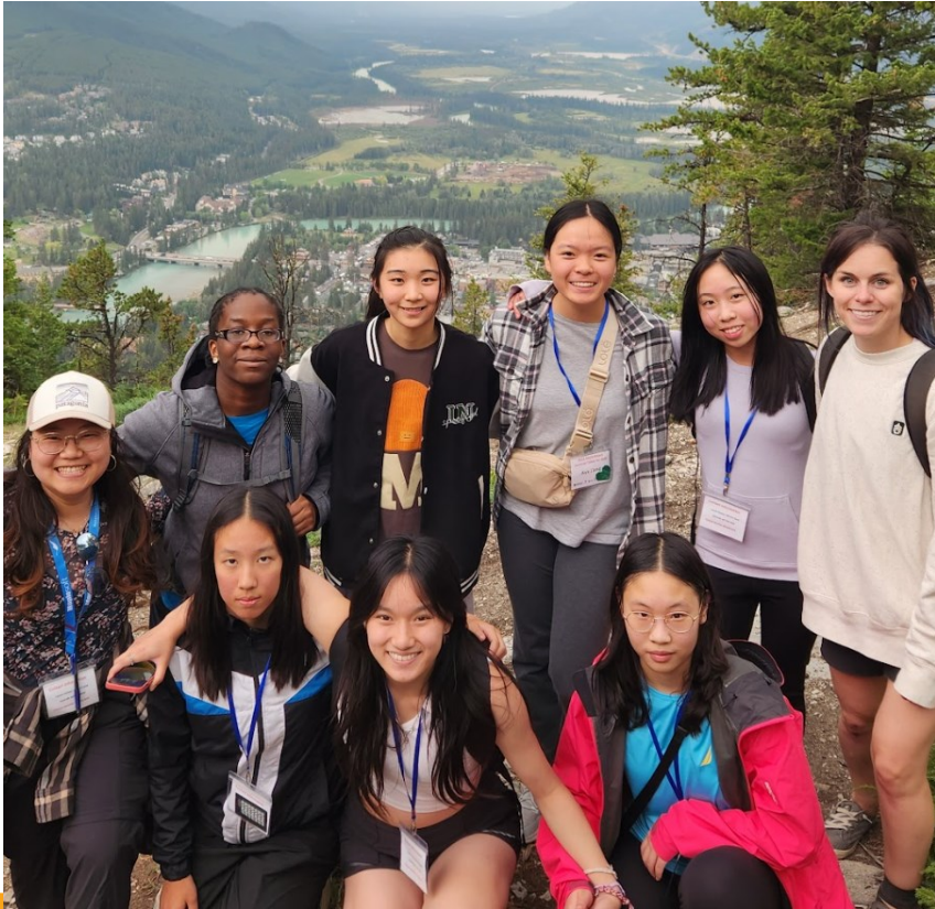 A group of girls in hiking clothes with a mountain valley behind them