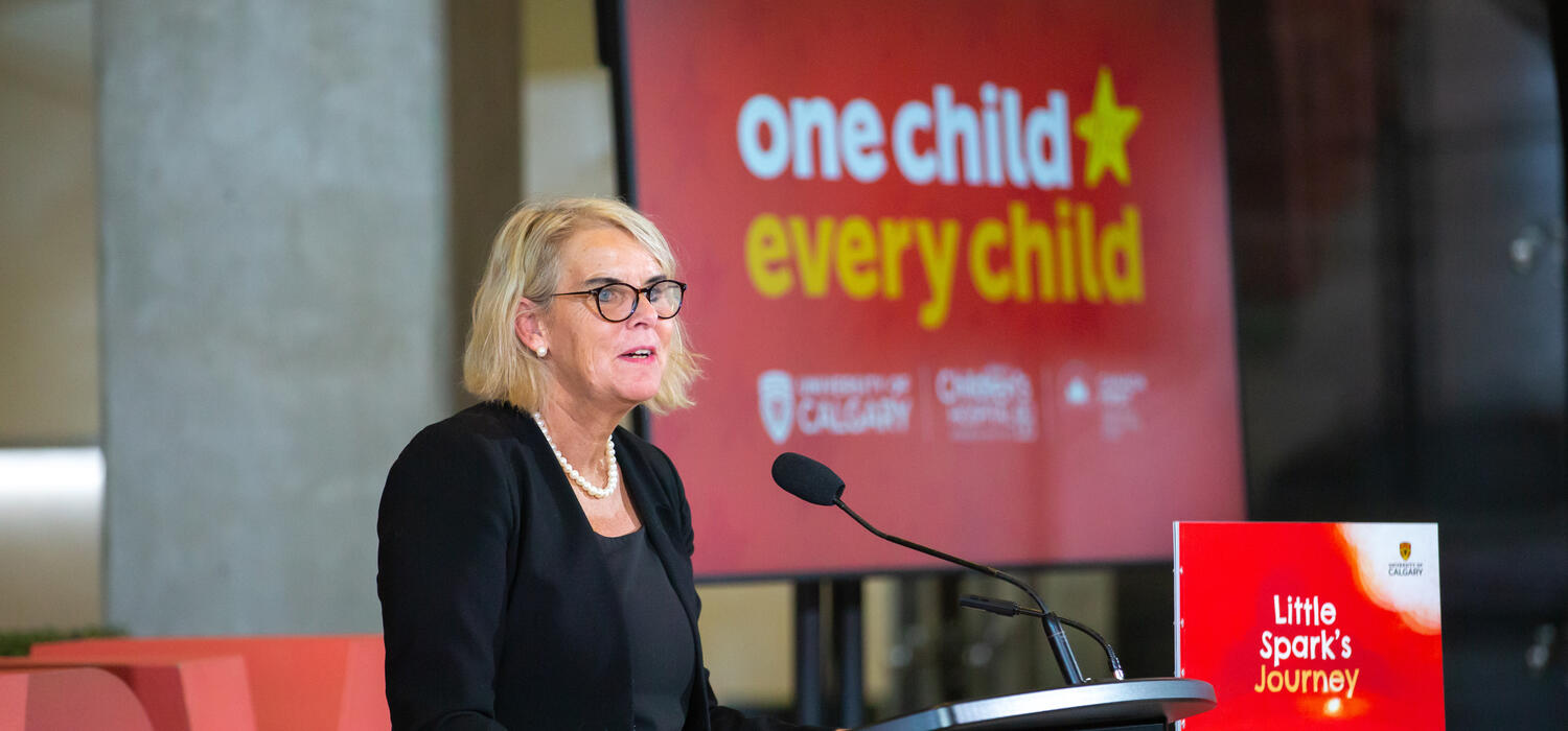 Dr. Susa Benseler speaks at a podium during the announcement of One Child Every Child