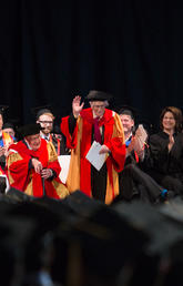 Dr. Richard Guy stands and waves as he is honoured at the 2016 UCalgary convocation ceremony for his 100th birthday.